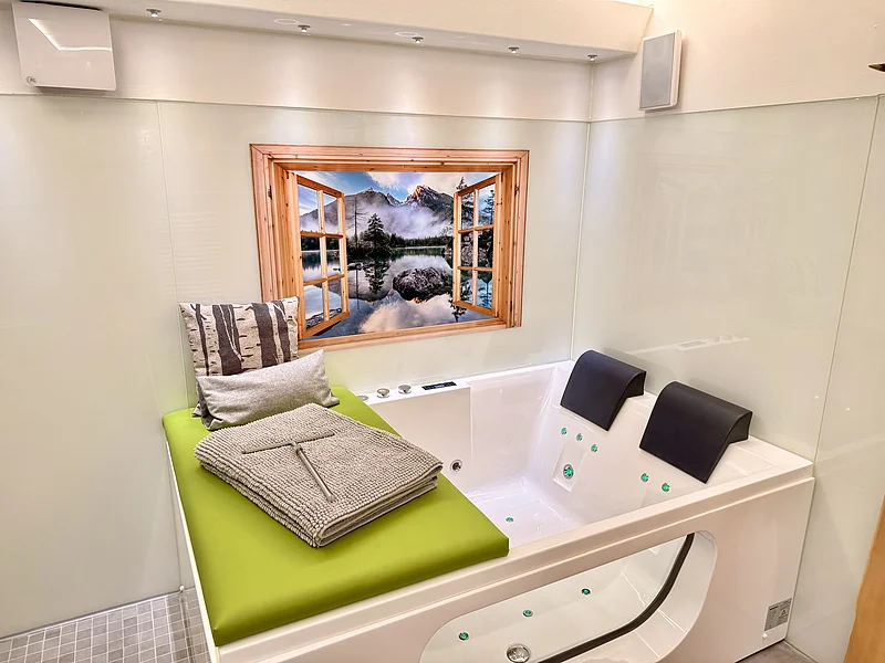 Whirlpool mit grüner Liegefläche, zwei Kopfstützen und Bild einer Landschaft an der Wand