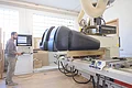 Schreinerei & Küchenstudio Gerstner - Maschine Mann bedient große CNC-Holzbearbeitungsmaschine in heller Werkstatt mit Steuergerät in der Hand.