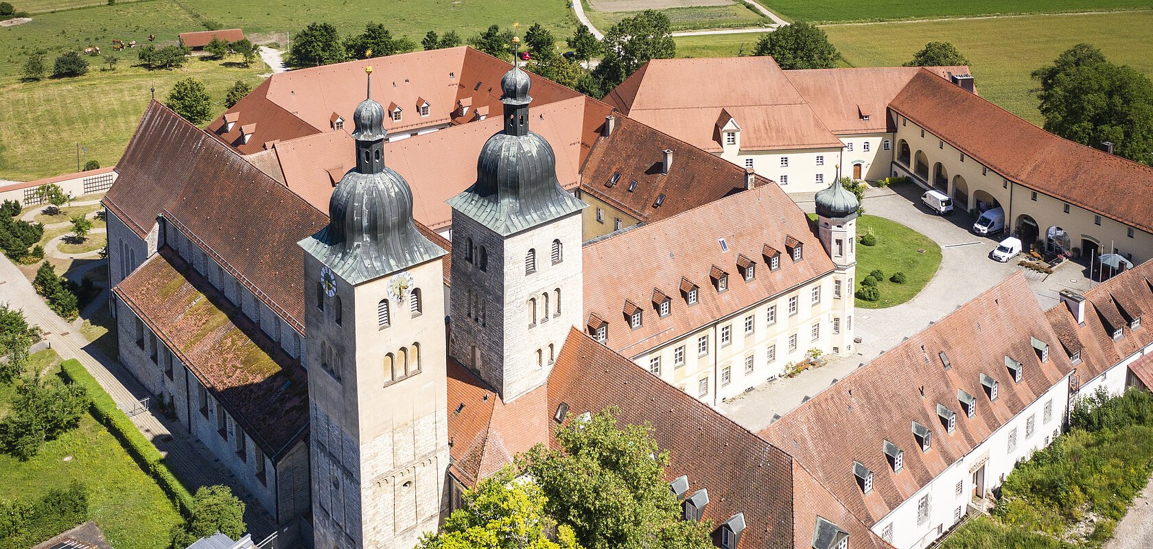 Das Kloster Plankstetten von oben mit der romanischen Kirche und den historischen Gebäuden, die sich vierseitig um den großen Kosterinnenhof stellen.