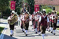 Dorferneuerung Flotzheim Stadtkapelle Musikzug in Trachten mit Blasinstrumenten und Fahnen bei einem Umzug auf einer Straße vor Häusern.