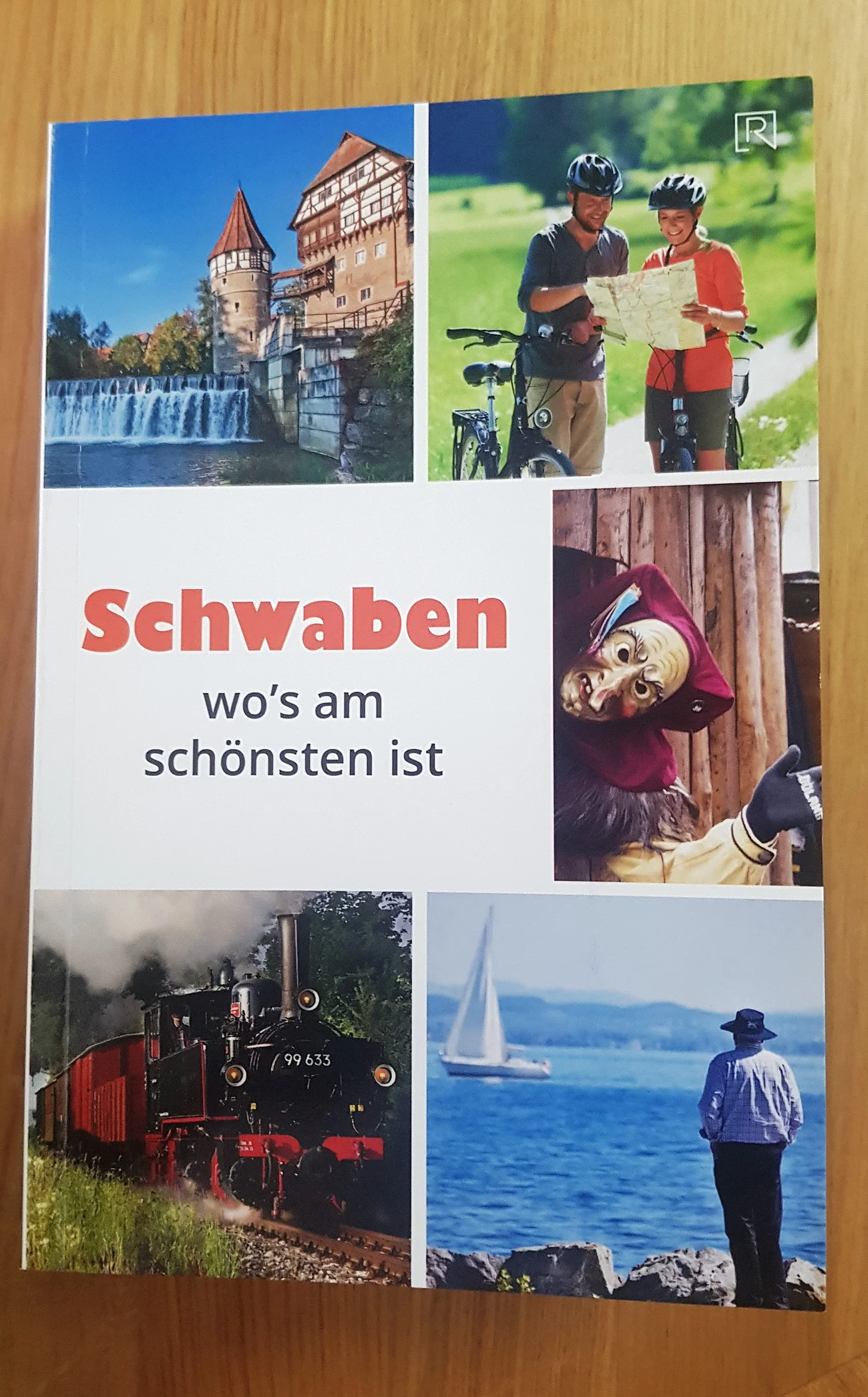 Reiseführer "Schwaben wo's am schönsten ist" Titelseite eines Reiseführers mit Fotos von einer Burg, Radfahrern, Fastnachtsmaske, Dampflok und Person am Seeufer. Titel in der Mitte "Schwaben wo's am schönsten ist".