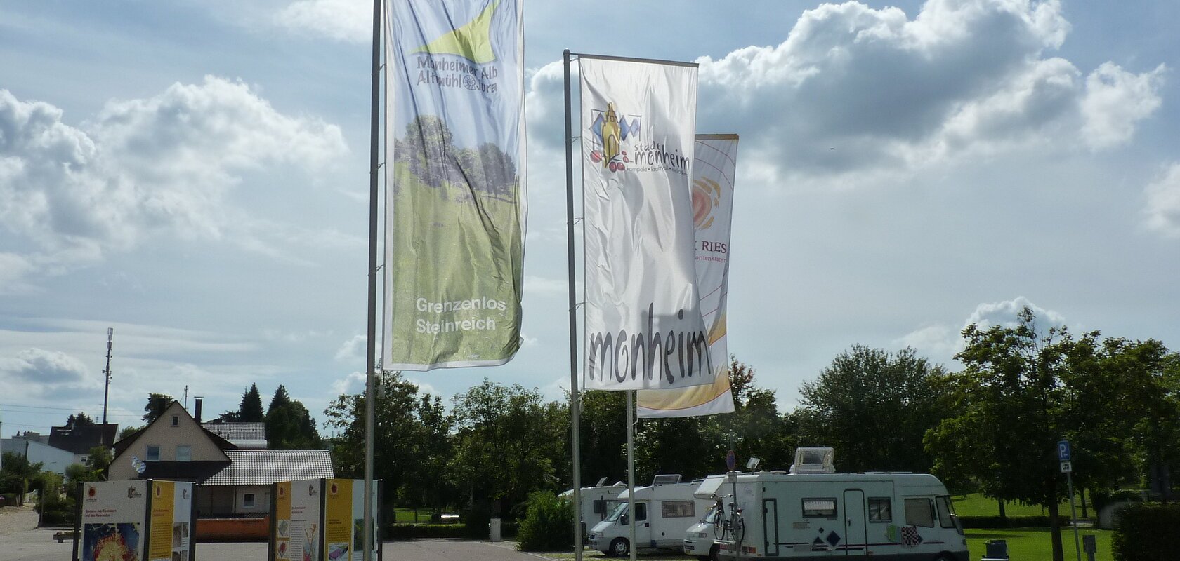 Die Geopark Infostelle mit Flaggen und im Hintergrund die Wohnmobile auf dem Wohnmobilstellplatz in Monheim