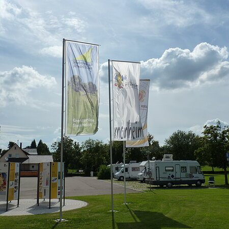 Die Geopark Infostelle mit Flaggen und im Hintergrund die Wohnmobile auf dem Wohnmobilstellplatz in Monheim