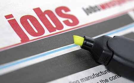 Zeitungsseite mit dem Wort "Jobs" in großen roten Buchstaben und einem gelben Textmarker daneben.