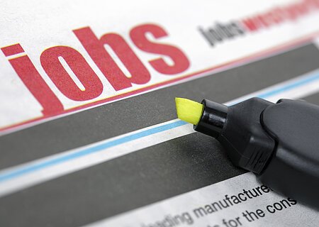 Zeitungsseite mit dem Wort "Jobs" in großen roten Buchstaben und einem gelben Textmarker daneben.