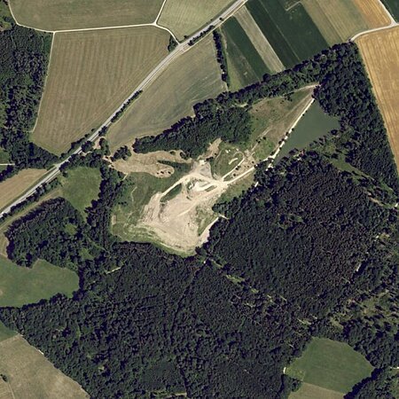 Luftaufnahme der Deponie Monheim:  Landschaft mit Feldern, Wäldern und einem unbebauten Gebiet in der Mitte.
