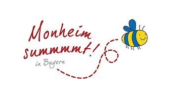 "Monheim summt!" - Partner des Netzwerks "Deutschland summt!" Logo vom Partner des Netzwerks "Deutschland summt!", nämlich "Monheim summt! in Bayern" mit dem gleichnamigen Schriftzug und einer lächelnden gezeichneten blau-gelben Biene. Rechts davon eine gestrichelte Fluglinie der Biene vom Schriftzug hin zu ihr.