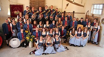 Musikverein Frohsinn Buchdorf e.V. - die Stammkapelle Gruppe von Menschen eines Musikvereins in traditioneller Kleidung mit Musikinstrumenten in einem Raum.