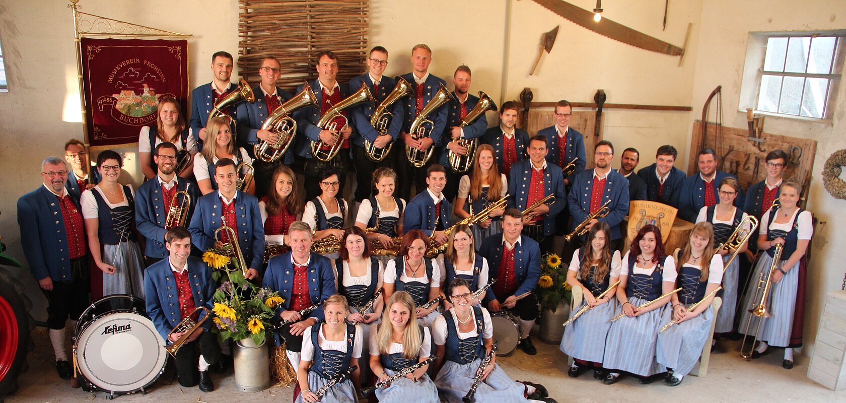 Gruppe von Menschen eines Musikvereins in traditioneller Kleidung mit Musikinstrumenten in einem Raum.