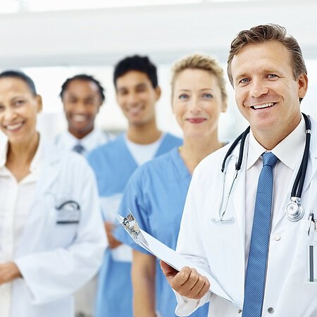 Gruppe von fünf Personen des medizinischen Fachpersonals in Kitteln und zwei davon mit Klemmbrettern.