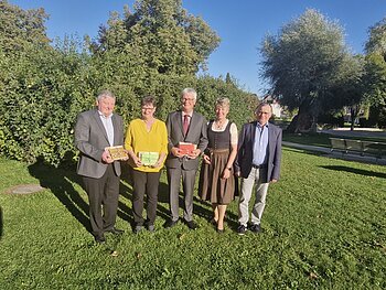 Verabschiedung Rentner 2025 Both Margit, Mayer Alfred, Josef Nuber Fünf Personen stehen auf einer Wiese vor Bäumen, drei halten bunte Geschenke in den Händen, im Hintergrund blauer Himmel. Renteneintritt der drei langjährigen Mitarbeiter der VG Monheim.