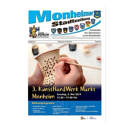 Titelblatt der Monheimer Stadtzeitung vom 3. Mai 2019 mit der dazugehörigen Überschrift in blau/schwarz, Wappen der Stadt Monheim und der dazugehörigen Stadtteile und mit dem Logo der Stadt Monheim. Auf der Titelseite die Ankündigung des 3. KunstHandWerk Markts am 5. Mai 2019. Auf dem Foto sind die Hände einer Person zu sehen, die ein Gefäß mit einem Pinsel anmalt.