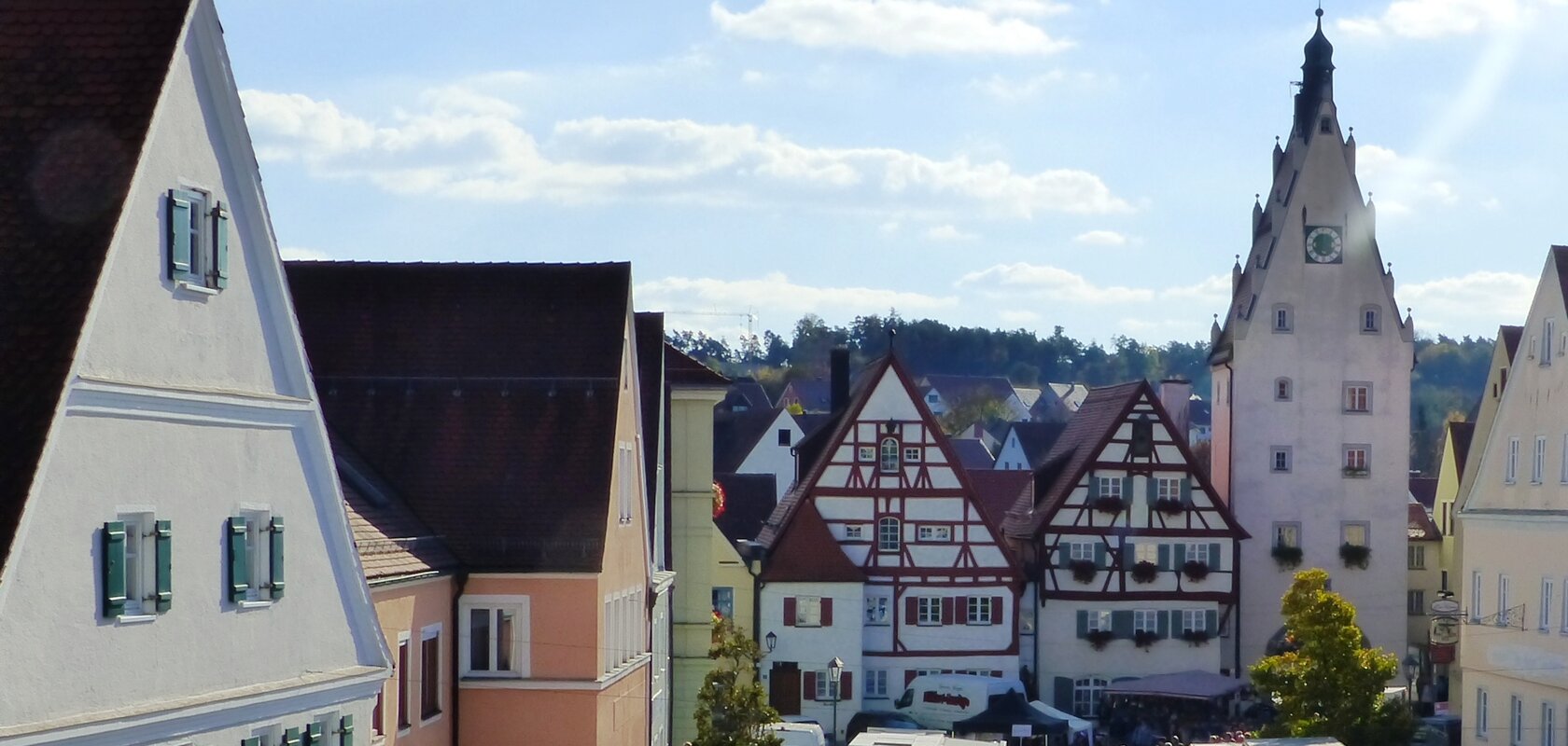 Menschenmenge auf dem belebten Monheimer Marktplatz mit historischen Gebäuden und vielen Verkaufsständen bei sonnigem Wetter.