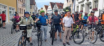 Große Gruppe von Radfahrern mit Helmen auf einer gepflasterten Straße mit Fachwerkhäusern in einer Altstadt bei dem jährlichen Stadtradeln.