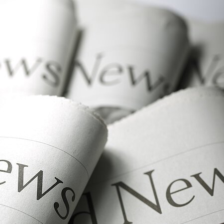 Nahaufnahme von fünf zusammengefalteten Zeitungen mit dem Wort „News“ auf der Titelseite.