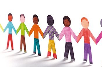 Papierfiguren, die Kinder symbolisieren in verschiedenen Farben halten sich an den Händen und bilden eine Kette.
