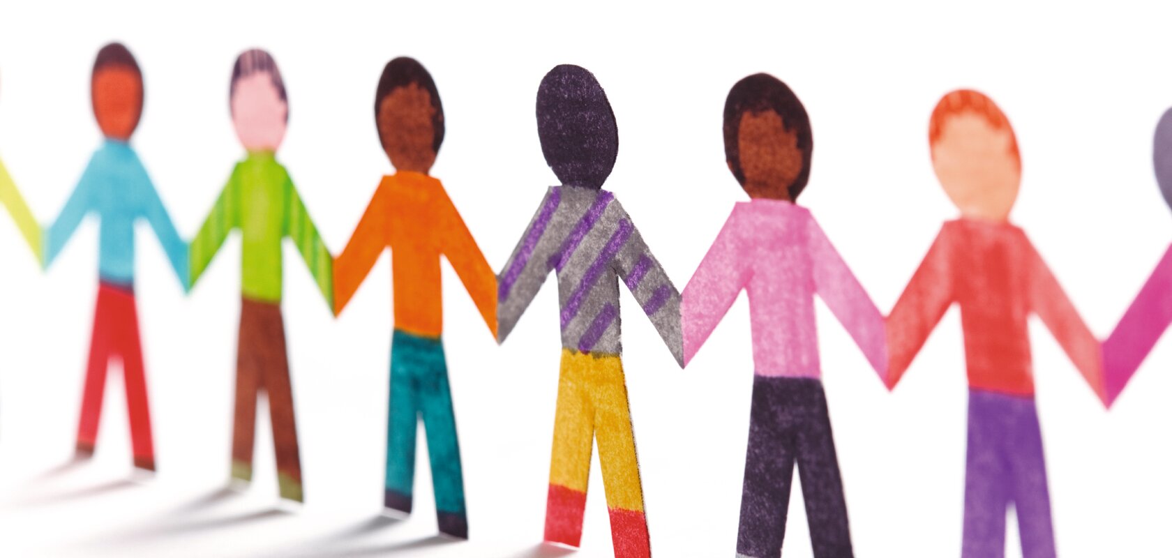 Papierfiguren, die Kinder symbolisieren in verschiedenen Farben halten sich an den Händen und bilden eine Kette.