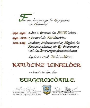 Urkunde der Stadt Monheim für Karlheinz Leinfelder zur Verleihung der Bürgermedaille 2018 mit Tätigkeitsangaben, Unterschriften und dem Wappen der Stadt Monheim.