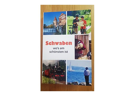 Titelseite eines Reiseführers mit Fotos von einer Burg, Radfahrern, Fastnachtsmaske, Dampflok und Person am Seeufer. Titel in der Mitte "Schwaben wo's am schönsten ist".
