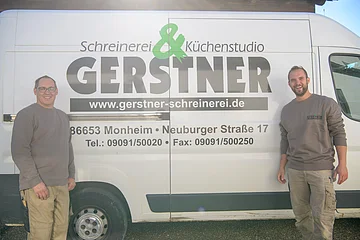 Zwei Männer stehen lächelnd vor einem weißen Transporter mit Werbung für Schreinerei Gerstner in Monheim.