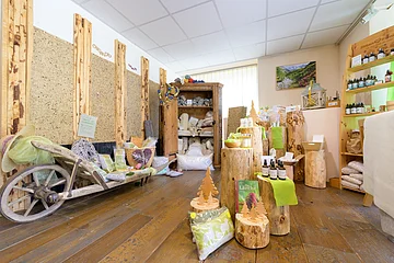 Innenraum eines Verkaufsraums mit Holzstämmen als Präsentationsflächen und Naturprodukten auf Holzboden.