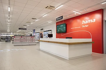 Innenansicht eines Hama Outlet Geschäfts mit Informationsschalter und Regalen für Smartphone- und Tablet-Zubehör.