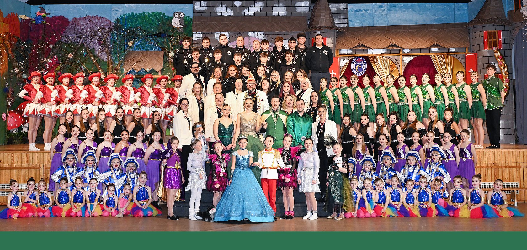 Gruppenfoto von FG Gailachia Monheim 2025 mit vielen Personen in bunten Kostümen auf einer Bühne vor einem Bühnenbild.