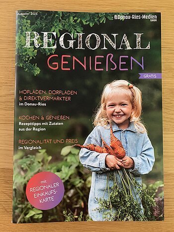 Titelblatt einer Broschüre mit einem lachenden Mädchen, das mehrere Karotten hält, und Text zu regionalen Hofläden und Rezepttipps.