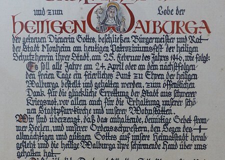 Ein handgeschriebenes Dokument mit dekorativen roten und schwarzen Buchstaben, das eine religiöse Widmung enthält. Hierin gelobt der Bürgermeister sowie der Rat der Stadt Monheim, ein alljährliches Dankamt zu Ehren der Heiligen Walburga abhalten zu lassen, für die Verschonung der Stadt im Zweiten Weltkrieg.