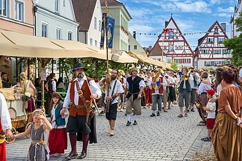 Menschen in historischen Kostümen und Musiker bei einem historischen Stadtfest mit Festumzug in einer Altstadt mit Fachwerkhäusern.