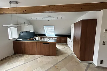 Miet-Maisonette - Moderne Küche mit Holzelementen, weißen Schränken, Dachfenster und Fliesenboden in einem Raum mit Holzbalken.