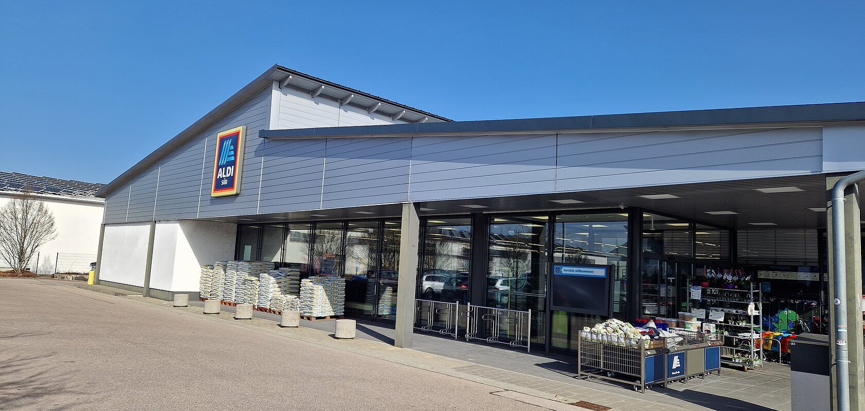 Außenansicht eines Aldi Süd Supermarkts bei sonnigem Wetter umgeben von einem Parkplatz.