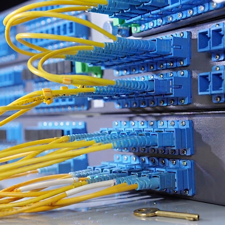 Gelbe Glasfaserkabel sind an blaue Netzwerkanschlüsse in einem Serverraum angeschlossen.