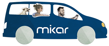 Blaues Auto mit zwei Personen und einem Hund, auf dem Auto der Schriftzug "mikar" auf der Seite. Fahrer hält das Lenkrad.