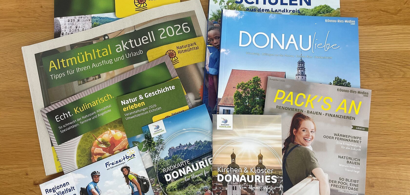 Mehrere Broschüren und Flyer zu Urlaub, Naturpark Altmühltal und Donau-Ries auf Holztisch liegend. Neuauflagen verschiedener Flyer und Broschüren in der Tourist-Information zur Abholung