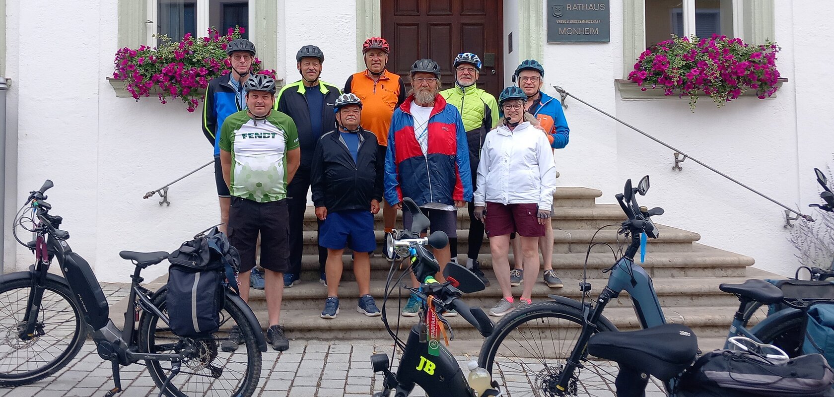 Neun Radfahrer mit Helmen stehen vor dem Rathaus Monheim, davor sind mehrere E-Bikes abgestellt. Auftakt zum Stadtradeln 2026 in Monheim