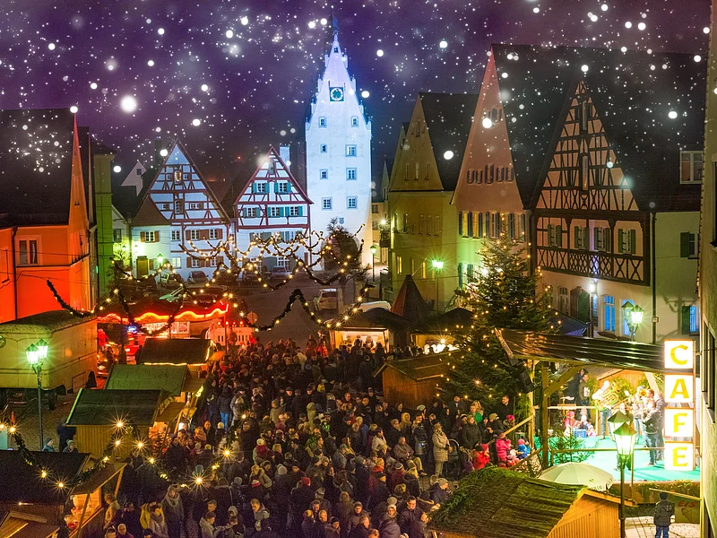 Romantischer Weihnachtsmarkt in Monheim Abendaufnahme des belebten Monheimer Weihnachtsmarktes in der Altstadt von Monheim: mit Fachwerkhäusern, Menschenmengen, Lichtern, Verkaufsständen und einer Bühne.