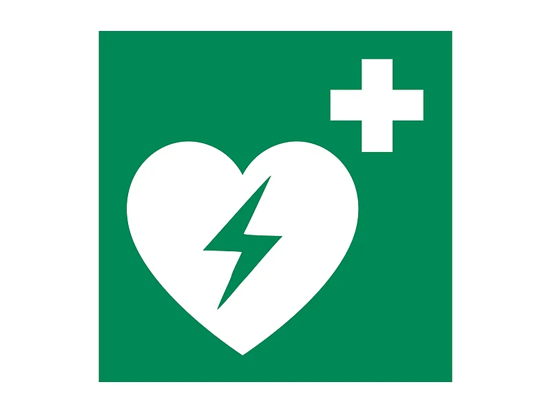 Symbol eines Defibrillators: ein Weißes Herz mit Blitz und weißes Kreuz auf einem grünem Hintergrund.