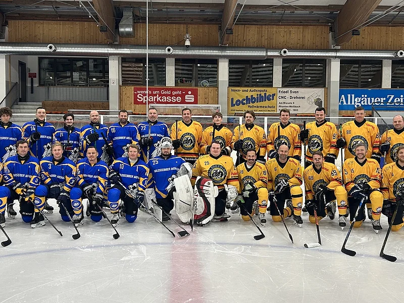 Eishockeymannschaft in blauen und gelben Trikots posieren gemeinsam auf dem Eis in einer Halle.