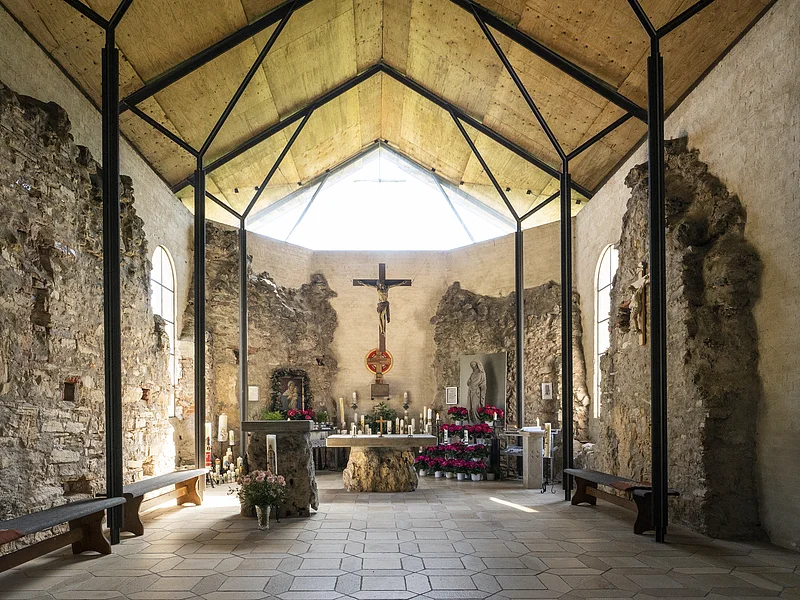 Ruinenkirche Spindeltal Innenraum einer Kapelle mit Altar, Kreuz, Kerzen und Blumen, umgeben von alten Steinmauern und Holzdecke