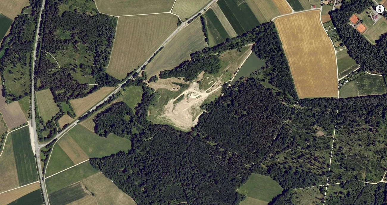Luftaufnahme der Deponie Monheim:  Landschaft mit Feldern, Wäldern und einem unbebauten Gebiet in der Mitte.