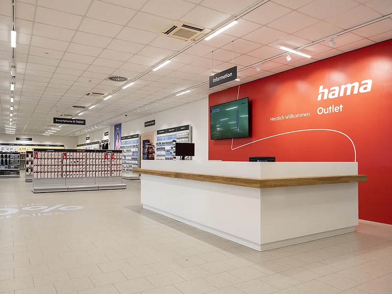Hama Outlet Innenansicht Innenansicht eines Hama Outlet Geschäfts mit Informationsschalter und Regalen für Smartphone- und Tablet-Zubehör.