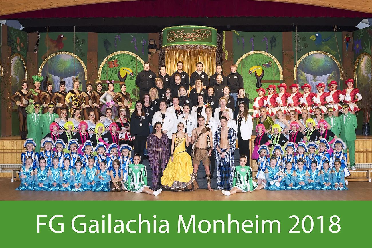 Gruppenfoto von der Faschingsgesellschaft  Gailachia Monheim aus dem Jahr 2018 mit vielen Personen in bunten Faschingskostümen vor einer Dschungelkulisse auf einer Bühne. Unten auf grünem Hintergrund in weißer Schrift der Schriftzug "FG Gailachia Monheim 2018".