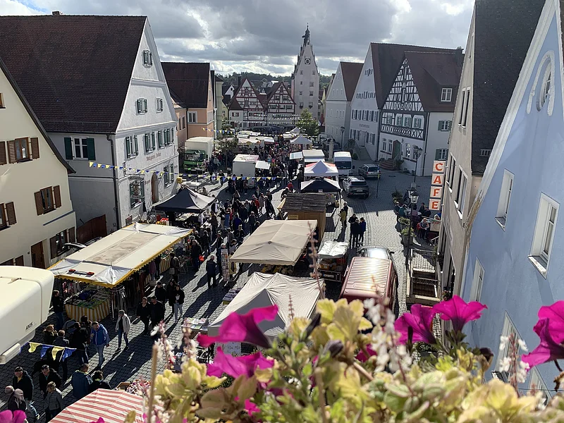Schärtlesmarkt in Monheim Blick von oben auf belebten Markt mit Ständen und Menschen in einer Altstadt mit Fachwerkhäusern und Café.