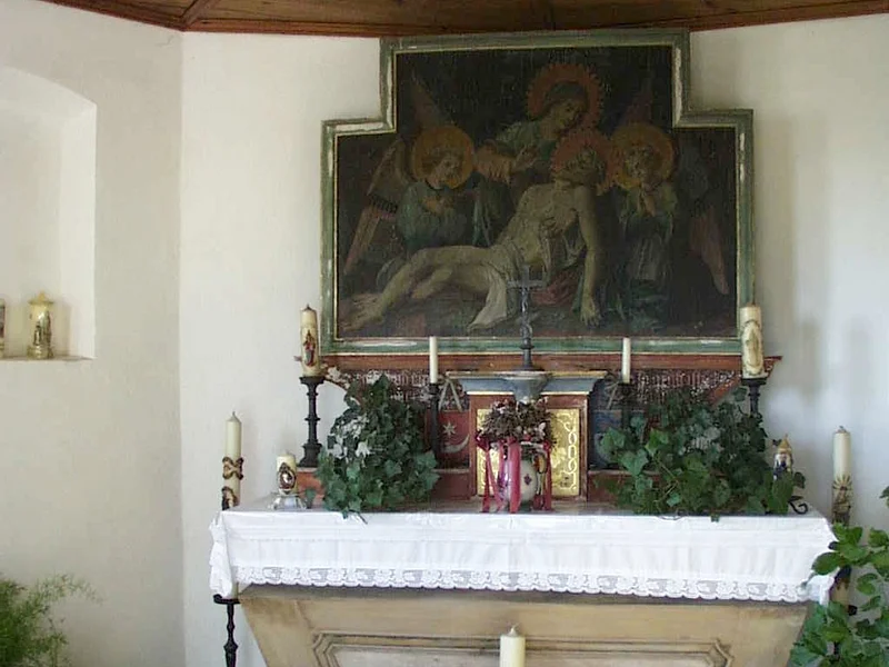 Altar in der Monheimer Brandkapelle Innenansicht einer Kapelle: Altar mit weißem Tuch bedeckt, umgeben von verschiedenen Kerzen, Blumen und religiösem Gemälde oberhalb an der Wand, in einem Raum mit Holzbalkendecke.