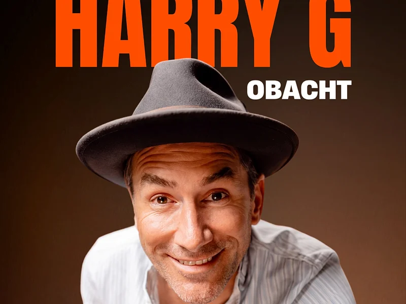 Mann mit grauem Hut und weißem Hemd zeigt mit Finger nach vorne, Text „HARRY G OBACHT“ im Hintergrund. Veranstaltung in der Monheimer Stadthalle am 26. April 2027