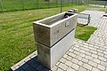 Armbecken der Kneipp Gesundheitsanlage in Monheim auf gepflastertem Weg neben einer Wiese, mit einem Wasserhahn an der Oberseite.