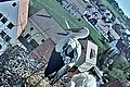 Zwei Weißstörche stehen in einem Nest mit drei Eiern auf einem Dach in einem Wohngebiet.