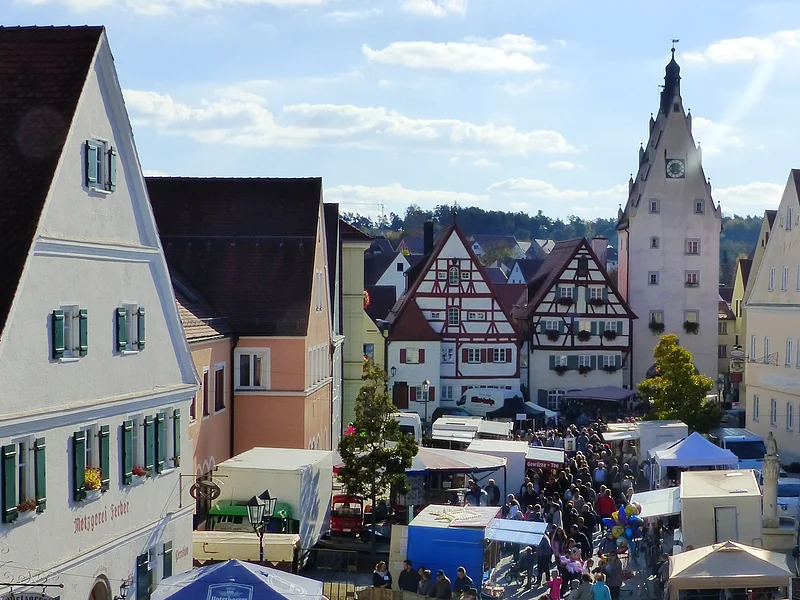 Schärtlesmarkt in Monheim Menschenmenge auf dem belebten Monheimer Marktplatz mit historischen Gebäuden und vielen Verkaufsständen bei sonnigem Wetter.