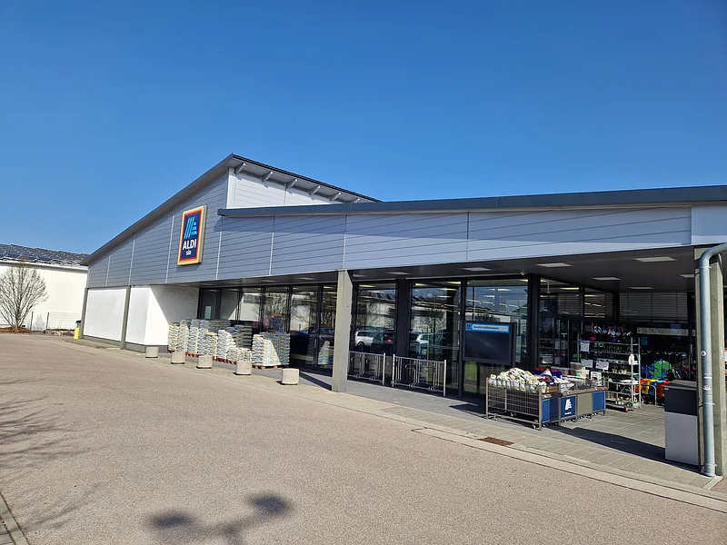 Aldi Süd - Ansprechende Filiale in Monheim Außenansicht eines Aldi Süd Supermarkts bei sonnigem Wetter umgeben von einem Parkplatz.